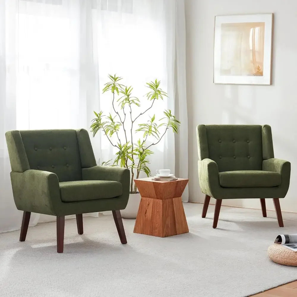 Pair of green upholstered armchairs with tapered dark legs in a bright room