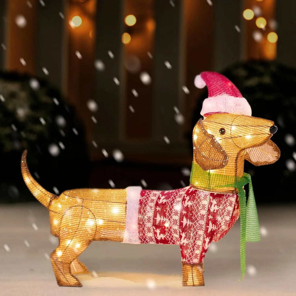 Kipwick lighted tan dachshund decoration with a Santa hat, red patterned sweater and green scarf in a snowy entryway