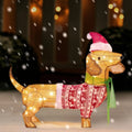 Kipwick lighted tan dachshund decoration with a Santa hat, red patterned sweater and green scarf in a snowy entryway