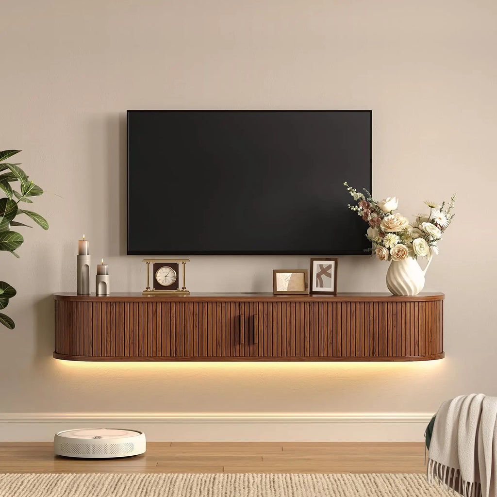 Walnut-finish Calyxcrest floating TV cabinet with closed fluted doors and warm lighting beneath, styled below a wall-mounted TV.