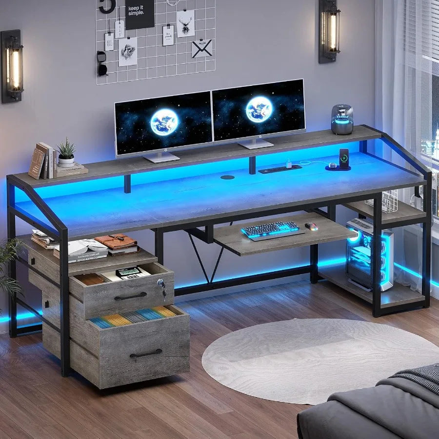 Gray computer desk with blue lighting, raised monitor shelf, keyboard tray, two drawers and open right shelves.