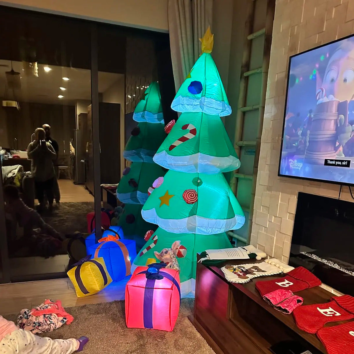 Tinselglow Christmas tree inflatable displayed indoors with its three attached gift accents.
