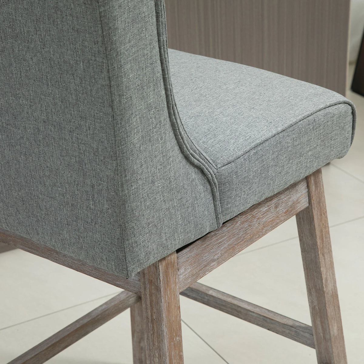 Close-up of Brynleigh gray upholstery, piped seat edge and wooden frame