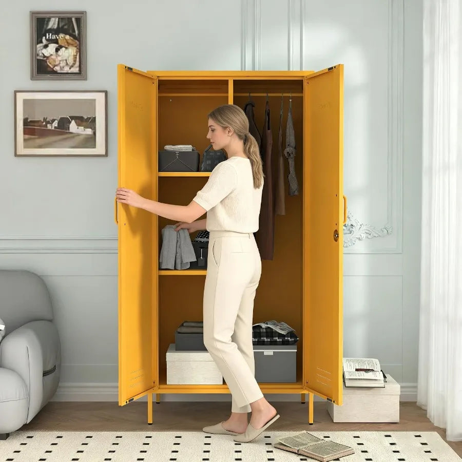 Open-door lifestyle view of the mustard armoire beside a person holding folded clothing.