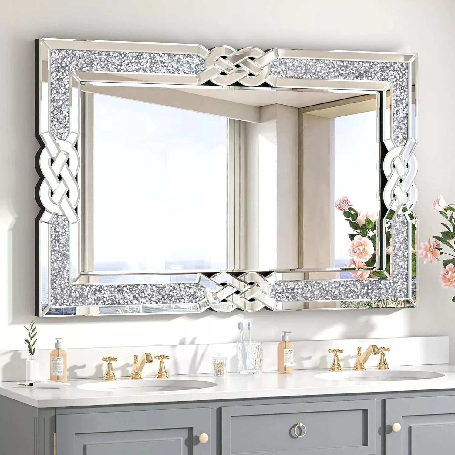 Decorative mirror with intricate frame above a bathroom vanity with gray cabinets and gold fixtures.