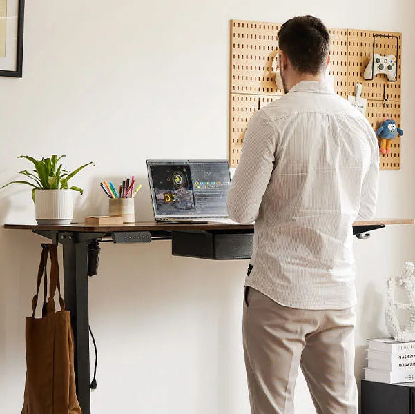 Person using a laptop at a standing desk in a home office setting.