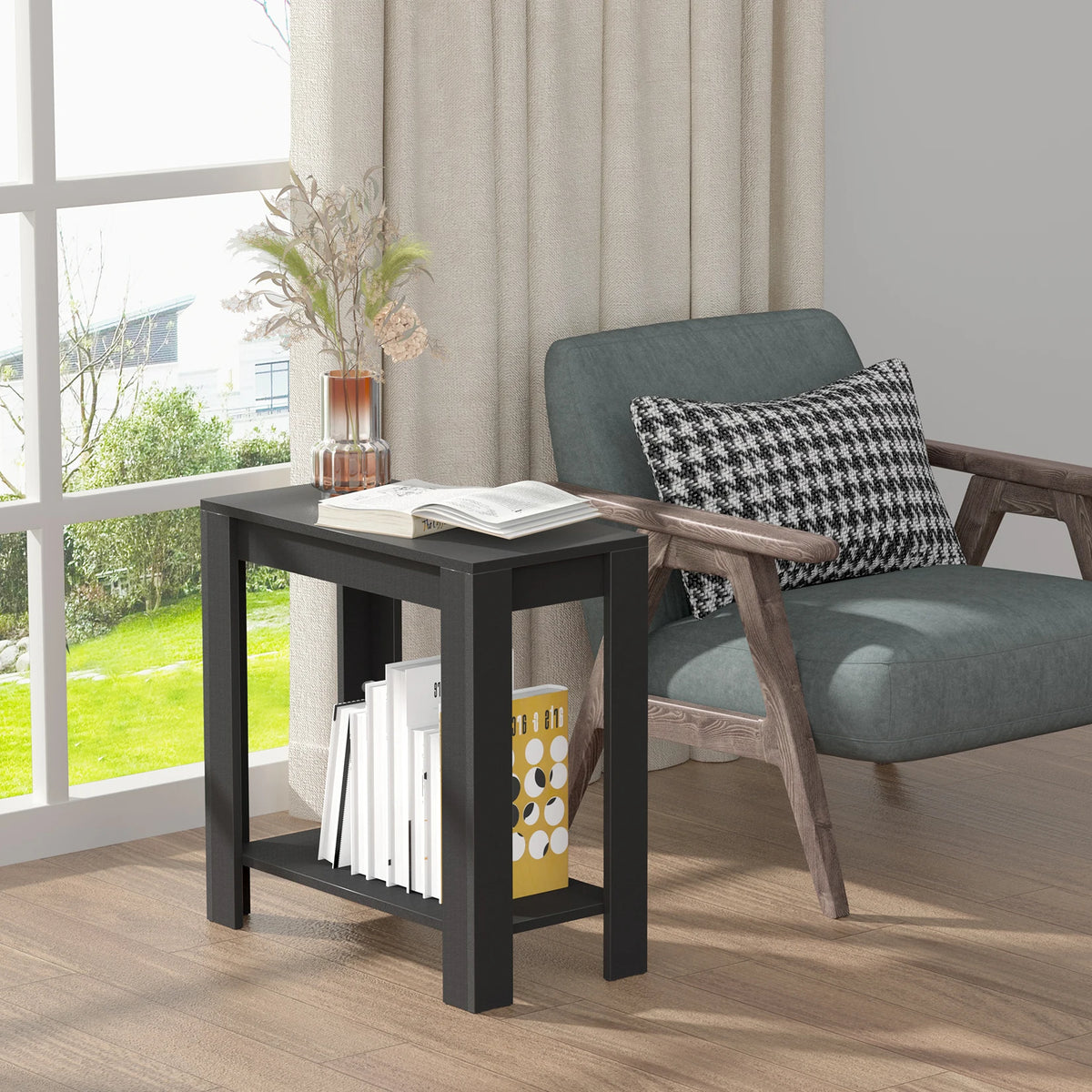 Rhapsodylark two-tier black side table beside an accent chair, styled with an open book and magazines.