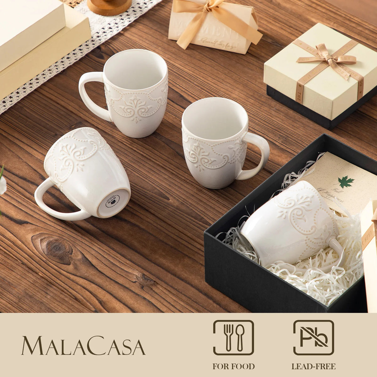 White embossed GISELLE mugs staged beside decorative gift boxes, with food-use and lead-free symbols