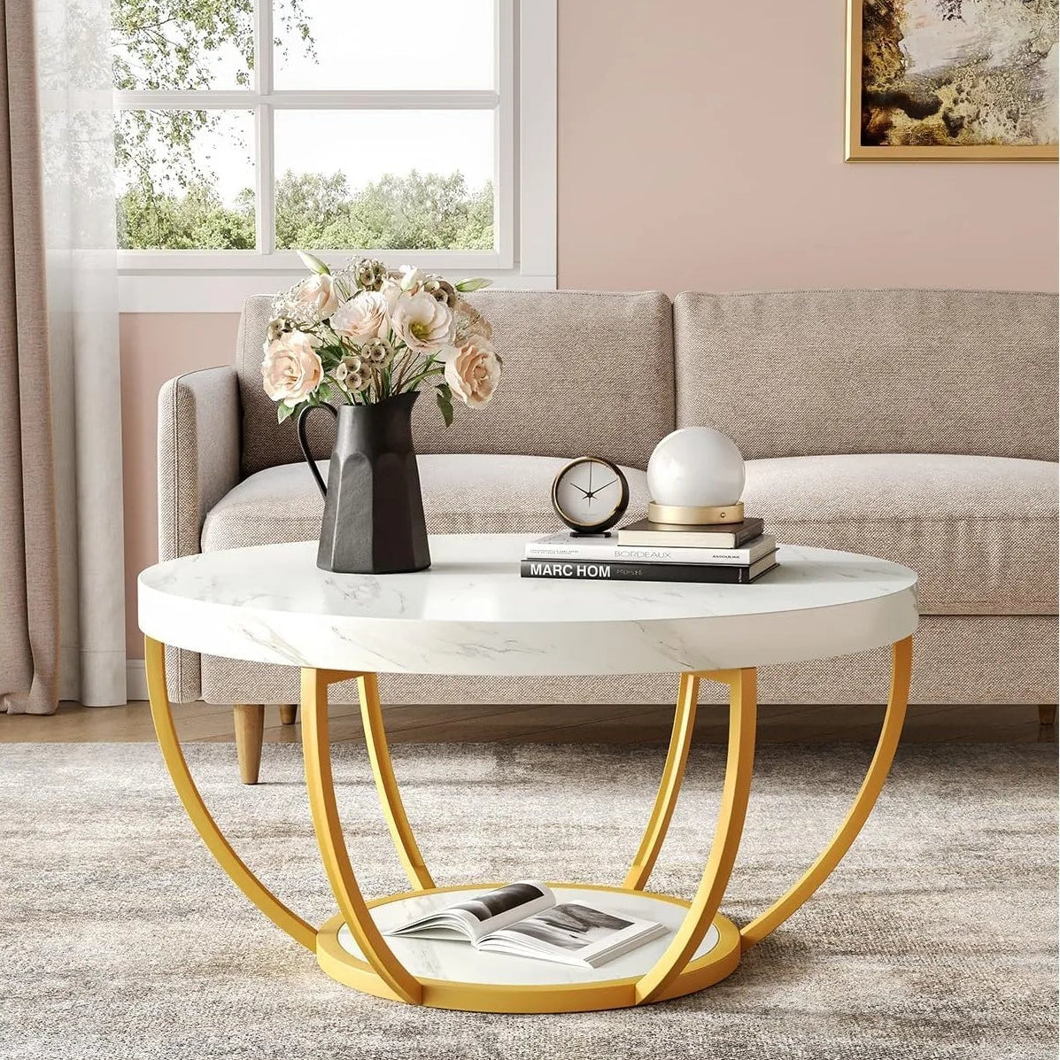 Round marble coffee table with gold legs in a living room setting.