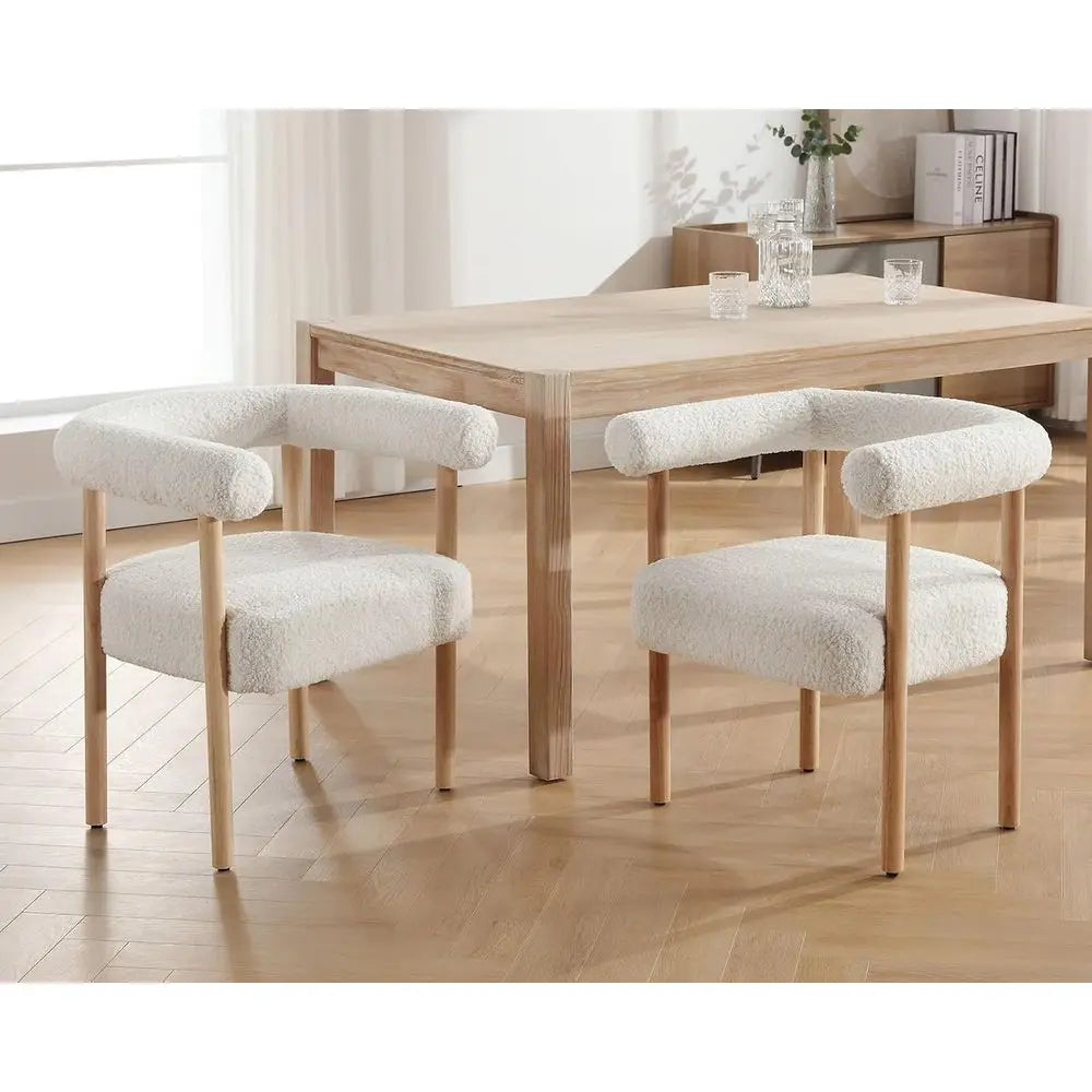 Dining table with two white cushioned chairs in a room with a window and shelves.