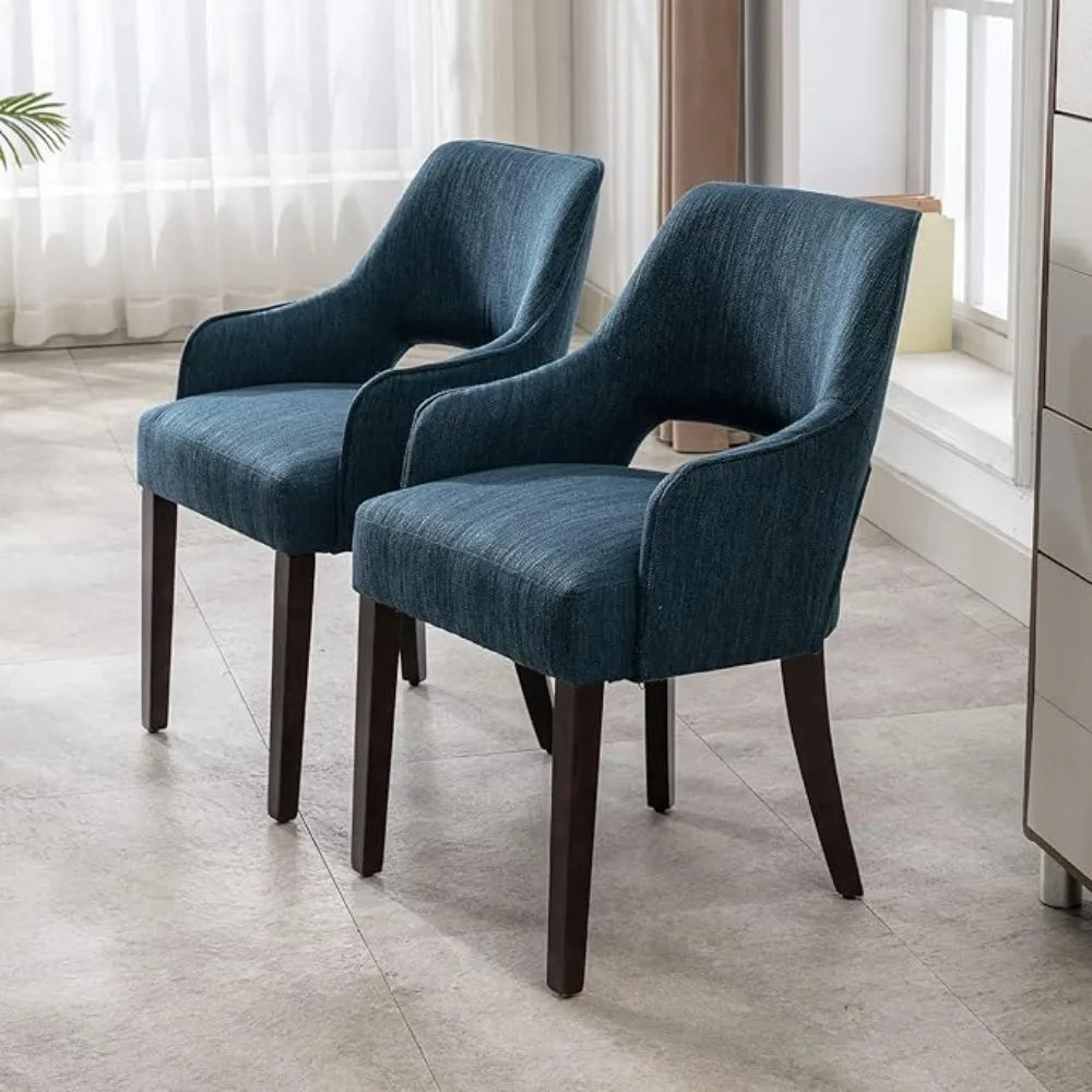 Two blue upholstered chairs with wooden legs in a room with light-colored flooring and a window in the background.