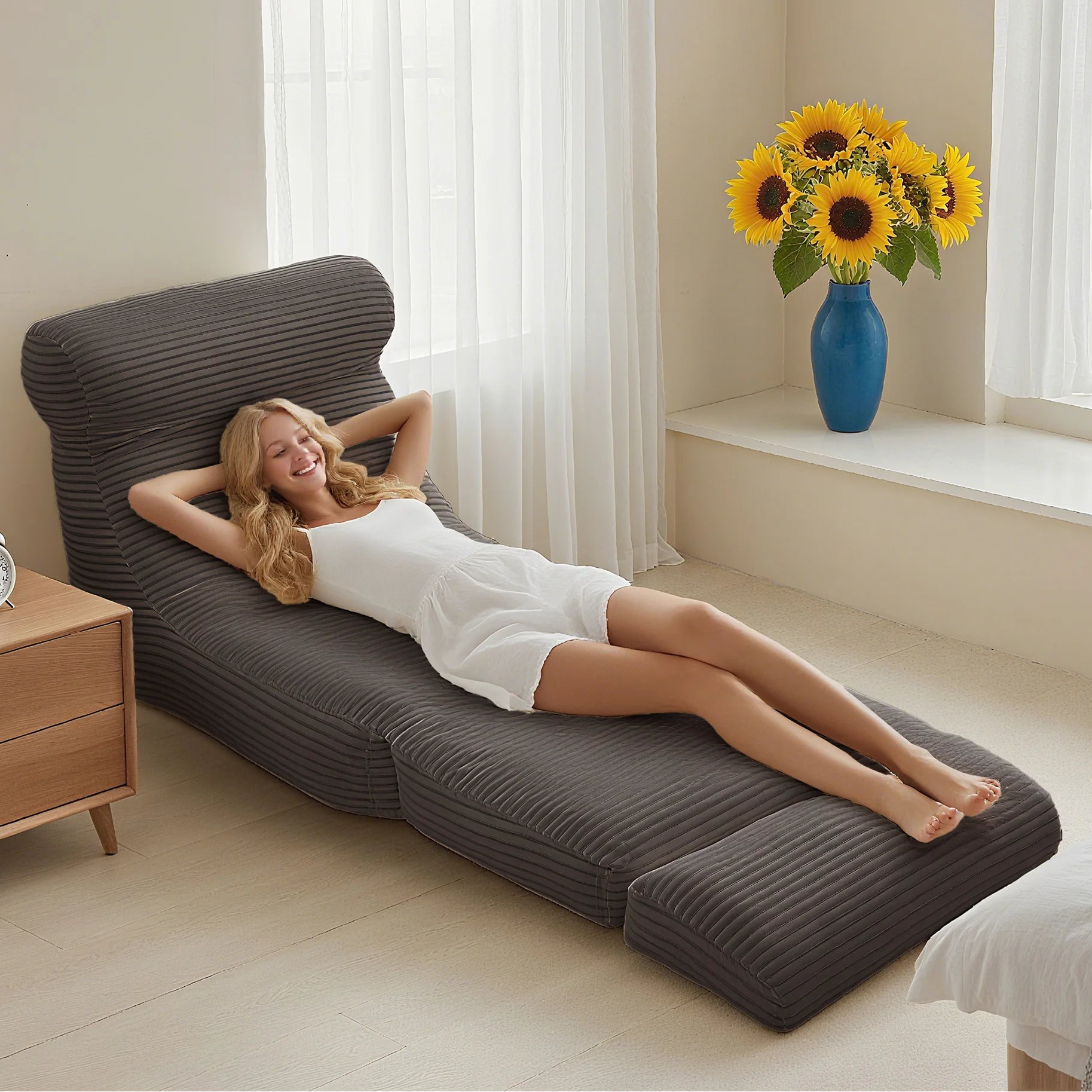 Woman relaxing on a modern lounge chair with 'Good Resilience' branding, sunflowers in a vase on a windowsill.