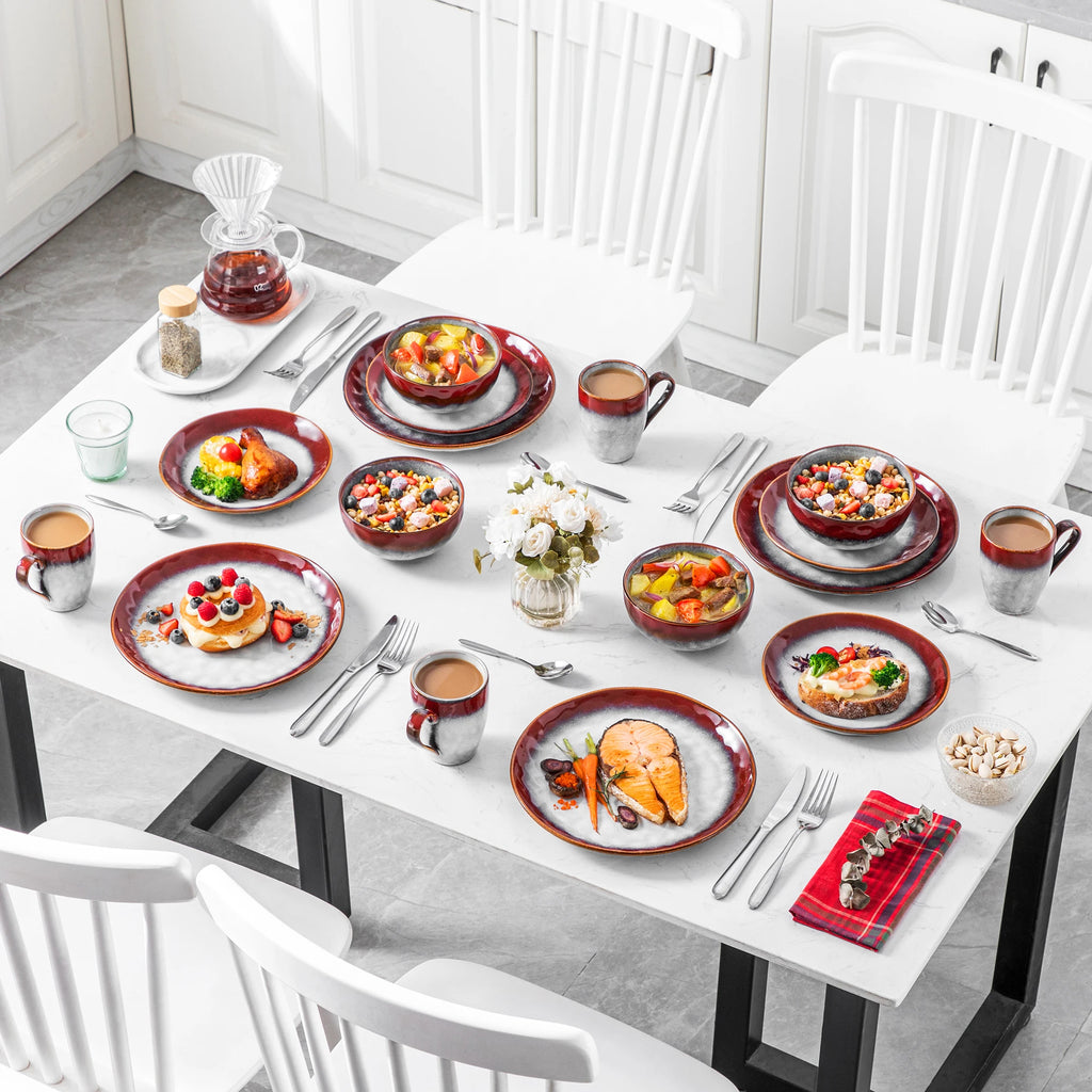 Red and gray dinnerware arranged with meals and drinks across a white dining table.