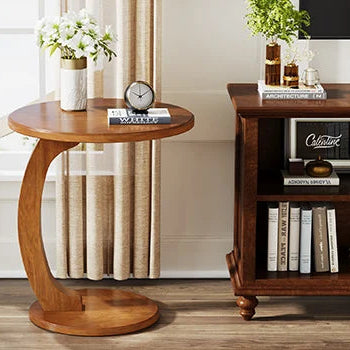 Wooden side table with a clock and vase next to a bookshelf in a room with a window and curtains.