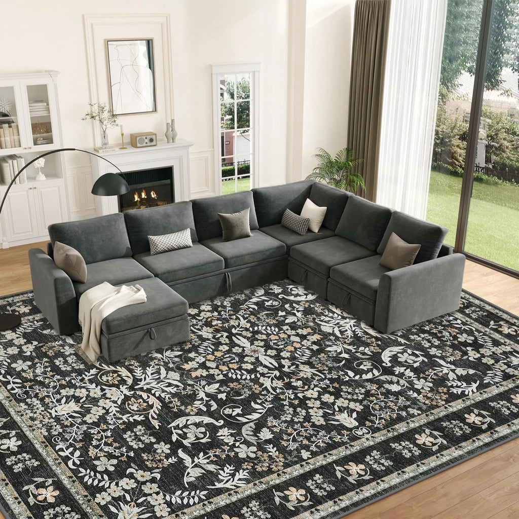 Gray sectional sofa in a living room with a decorative rug and fireplace.