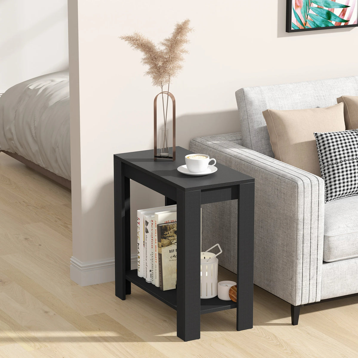 Rhapsodylark narrow black side table with books and small accessories on its lower shelf beside a sofa.