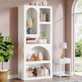 White bookshelf with decorative items in a room with a lamp and plant.