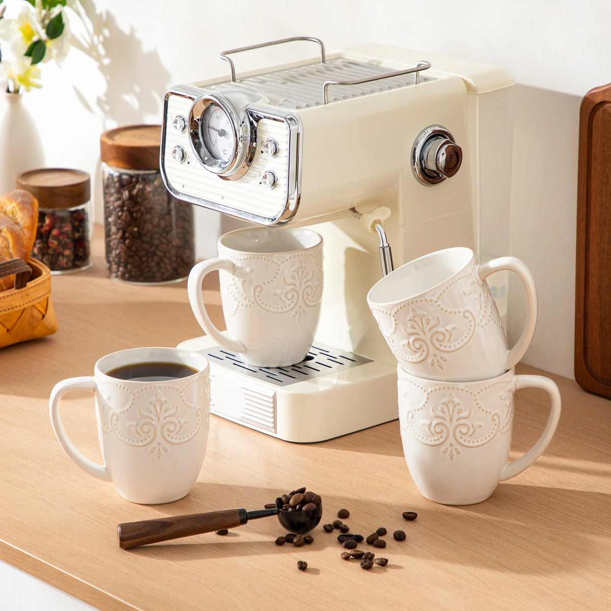 White embossed GISELLE mugs arranged around an espresso machine on a kitchen counter
