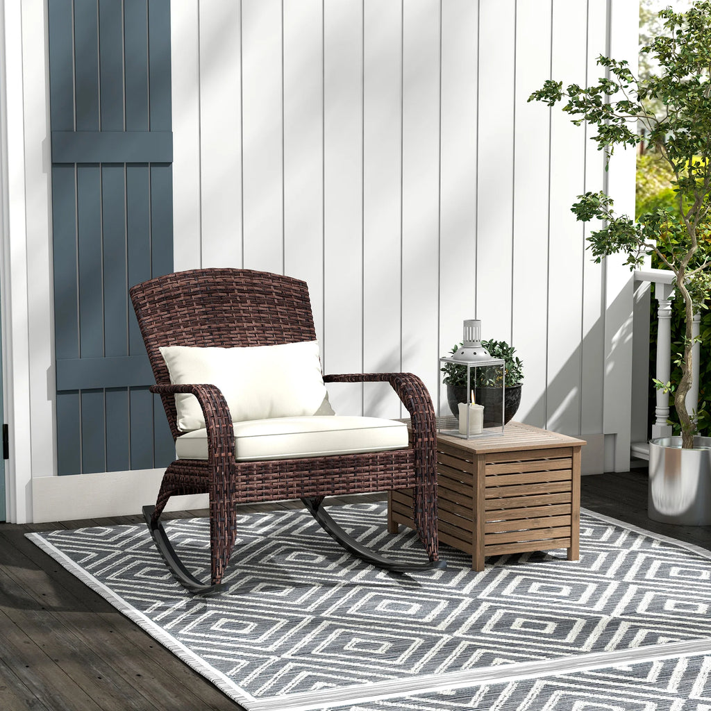 Brown woven rocking chair with a cream seat cushion and back pillow on a porch beside a small table.