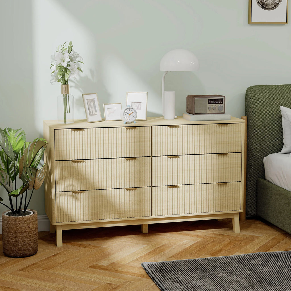 Sunbeamcrest fluted dresser with gold-tone finger pulls beside a bed.