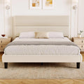 Beige upholstered platform bed with a two-panel padded headboard in a bedroom