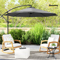 Gray cantilever patio umbrella shading two chairs in an outdoor garden seating area
