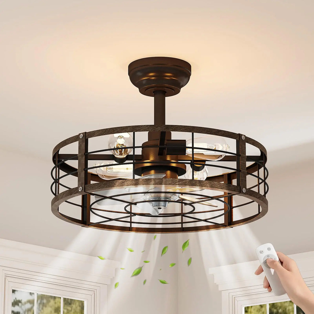 A semi-flush mount ceiling fan light with an antique bronze finish and a circular wire cage, shown installed in a ceiling. A hand is holding a white remote control in the lower right corner, and green leaf graphics are floating near the light rays shining downward.