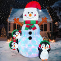 Snowlisse: Snowman inflatable with a Santa hat, striped scarf and three penguins illuminated in a snowy yard