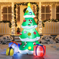 Tinselglow Christmas tree and attached gifts illuminated beside a porch at night.