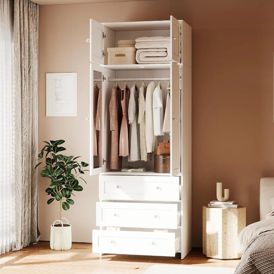 Open-door bedroom view of the tall white wardrobe with hanging clothes and stacked linens.