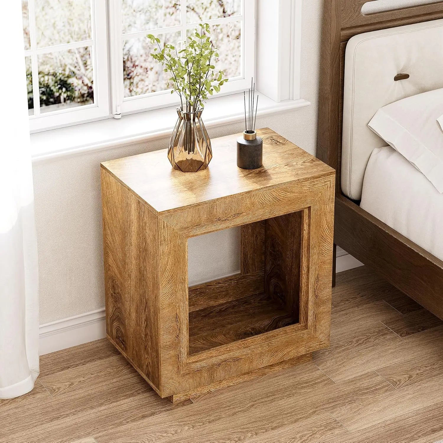 Wooden nightstand with decorative items next to a bed in a bedroom.