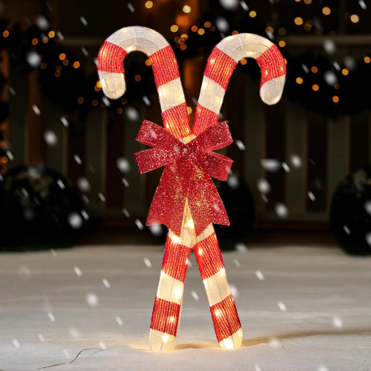 Bowglint crossed red-and-white candy canes with a red bow illuminated by warm white lights.