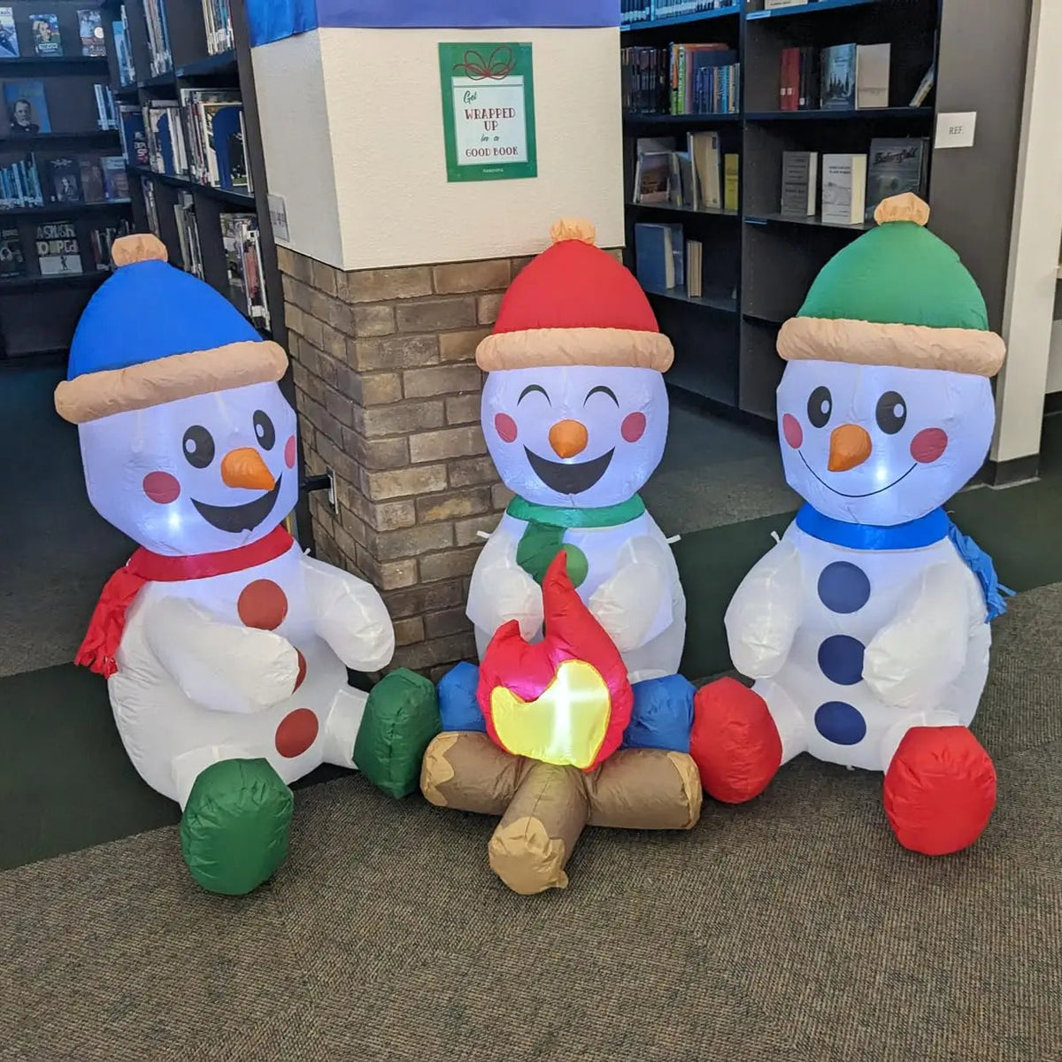 Snowmingle campfire scene with three snowmen and colorful winter accessories displayed indoors.